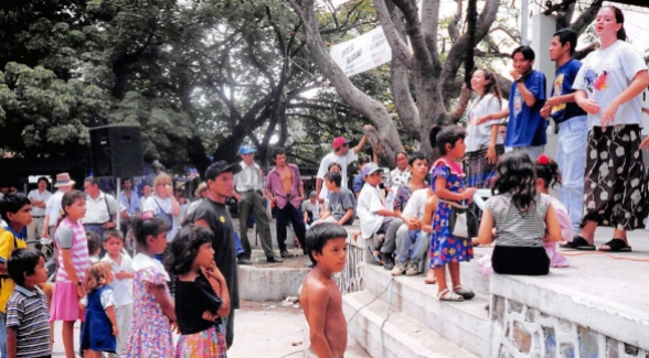 a group of children and adults watching people on a stage outdoors