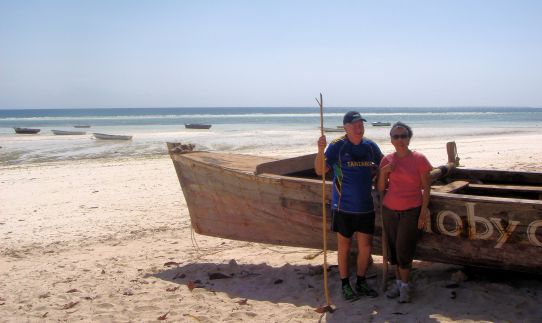man and woman next to a wooden boat on a beach
