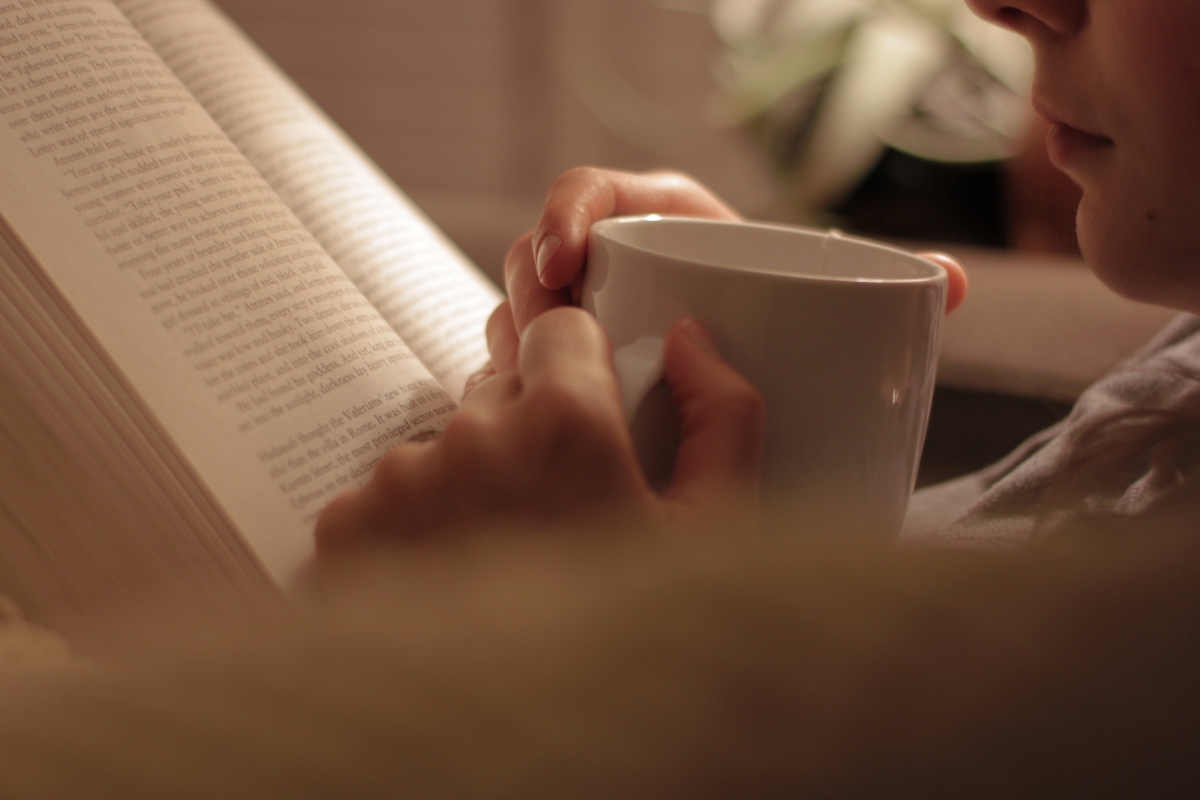 man reading a book and drinking coffee