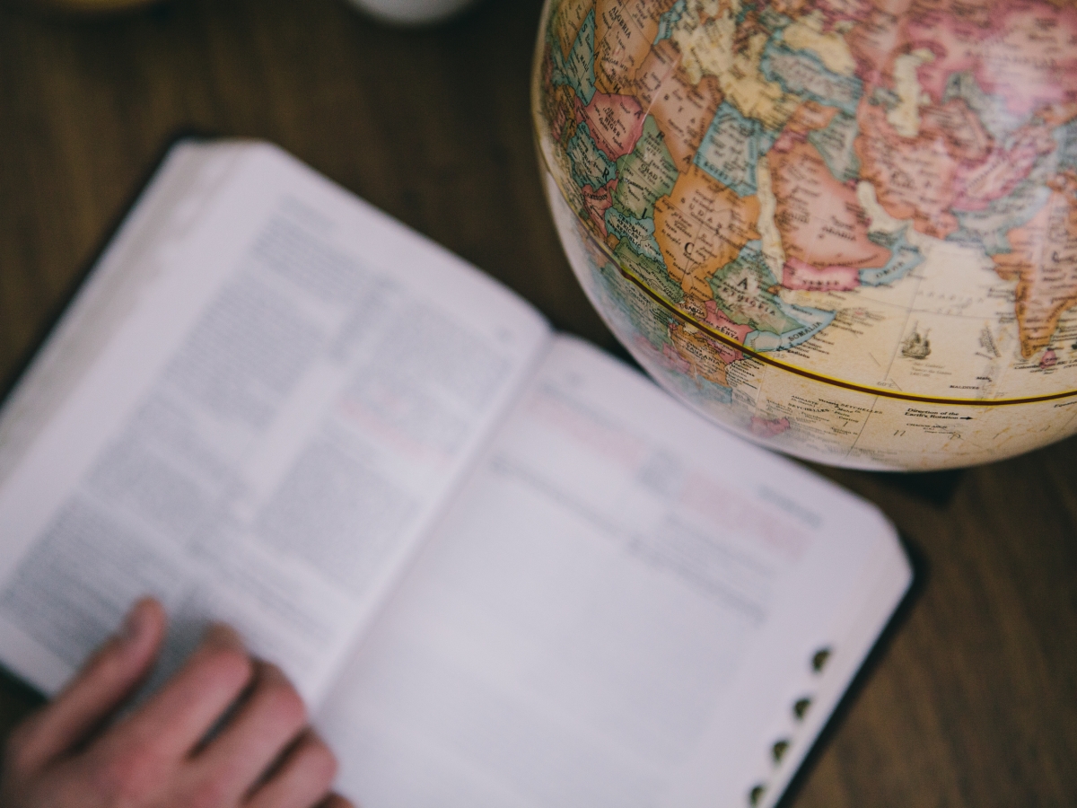 an open Bible next to a world globe
