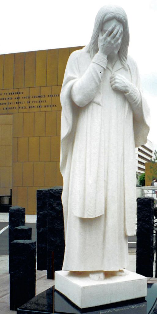 a statue of Christ, hand covering His face 